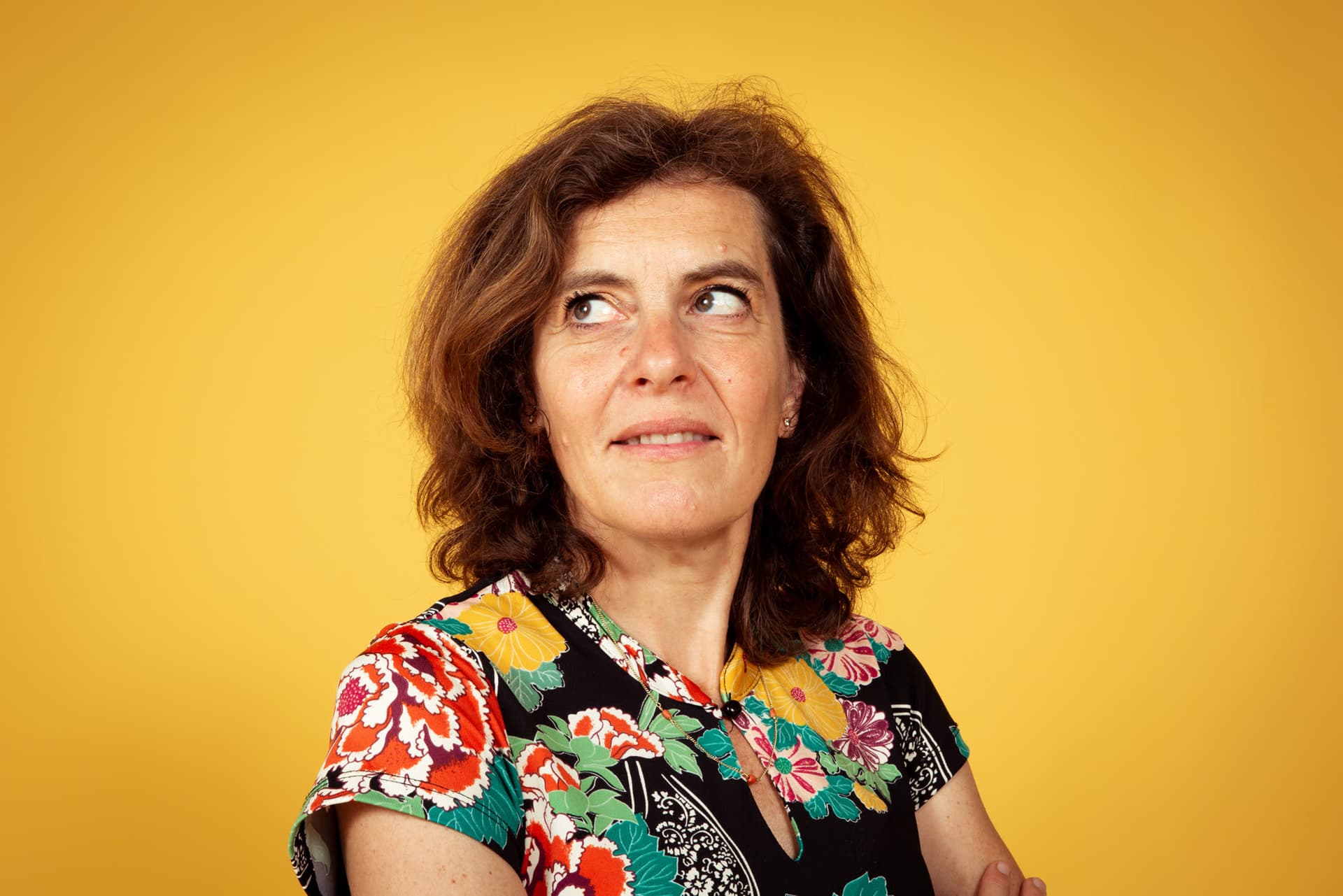 Emily kijkt lachend opzij tegen een gele achtergrond.