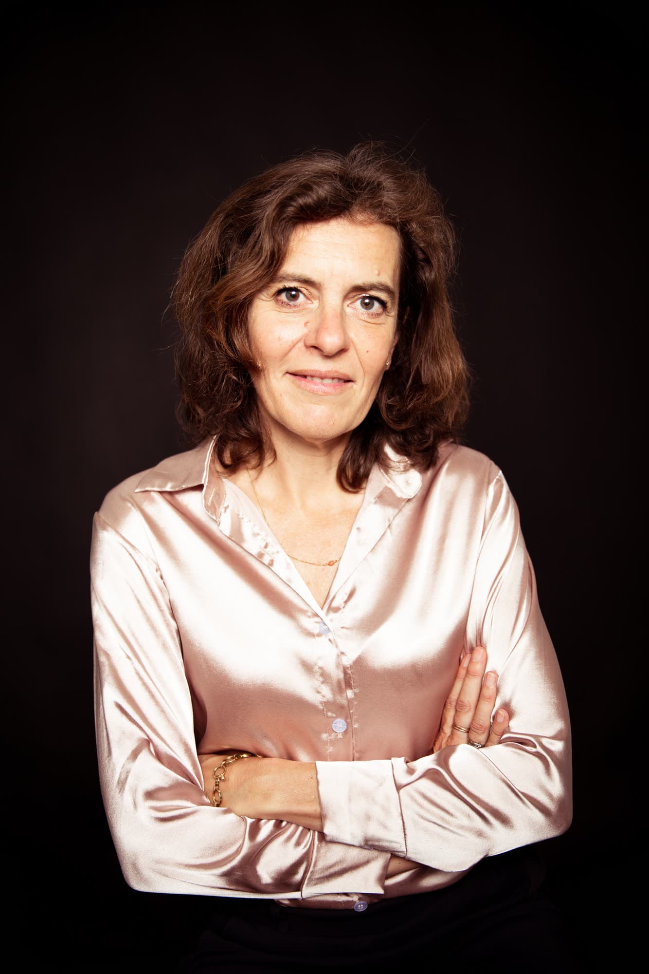Emily Staphorst met over elkaar geslagen armen tegen een donkere achtergrond